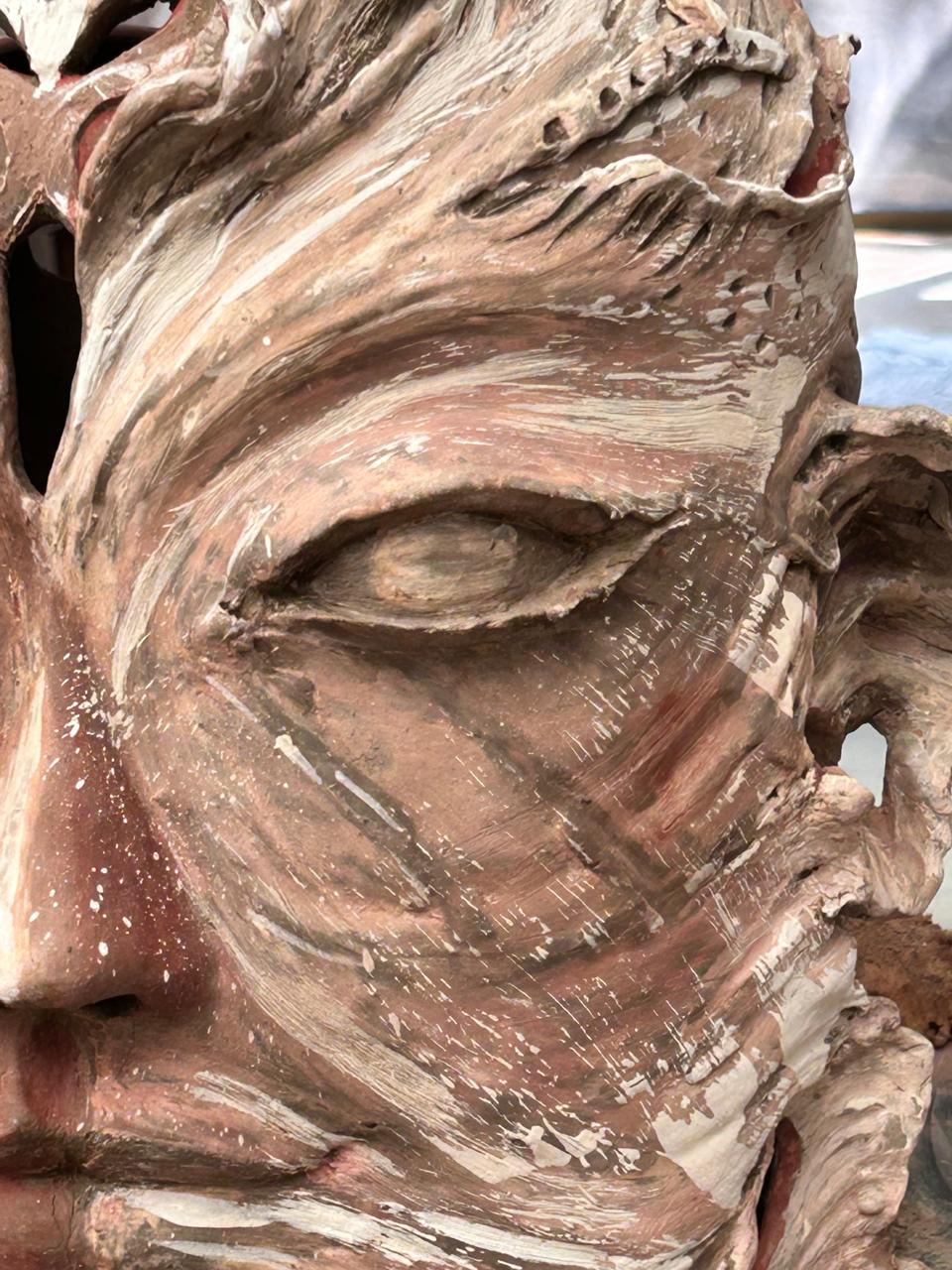 A close view of a terracotta sculpture, with flowing ridges and pale textured details